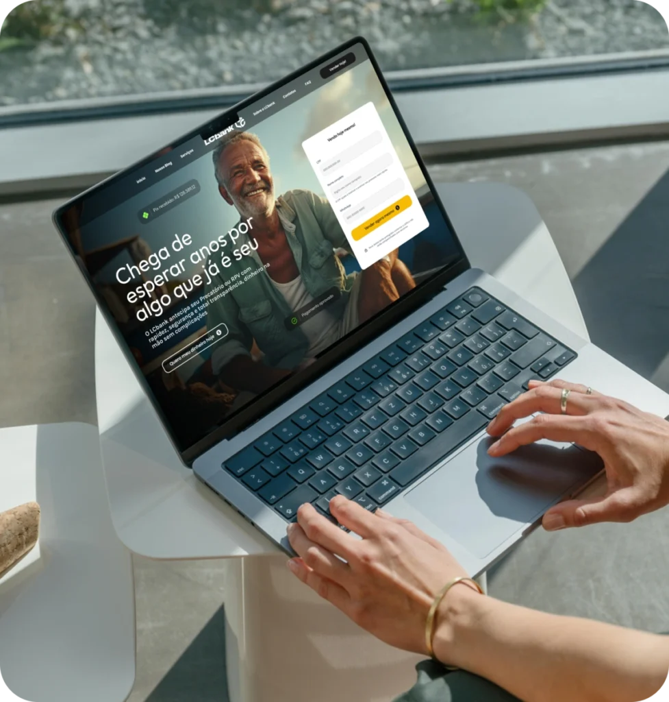 Laptop aberto exibindo site do LCbank com login e título "Chega de esperar por algo que já é seu